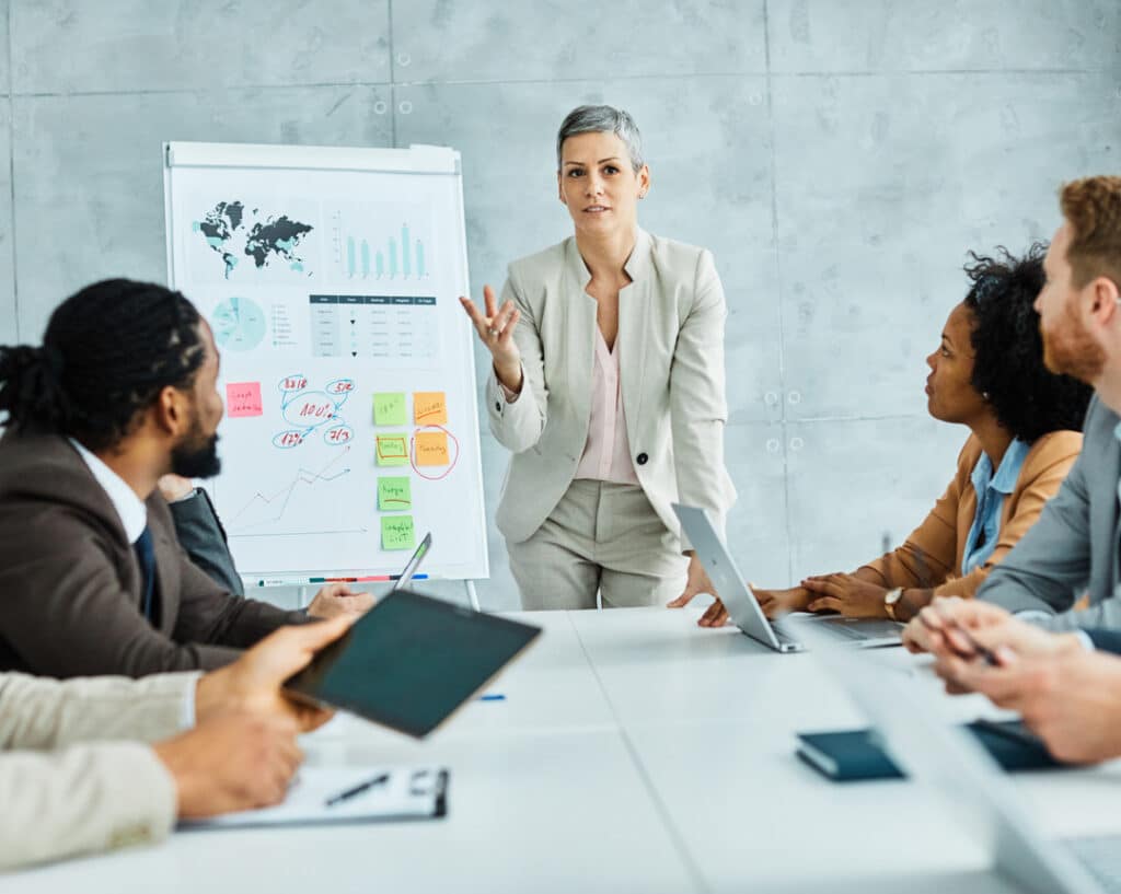 Young coworkers meet in front of a whiteboard to form a business continuity plan.