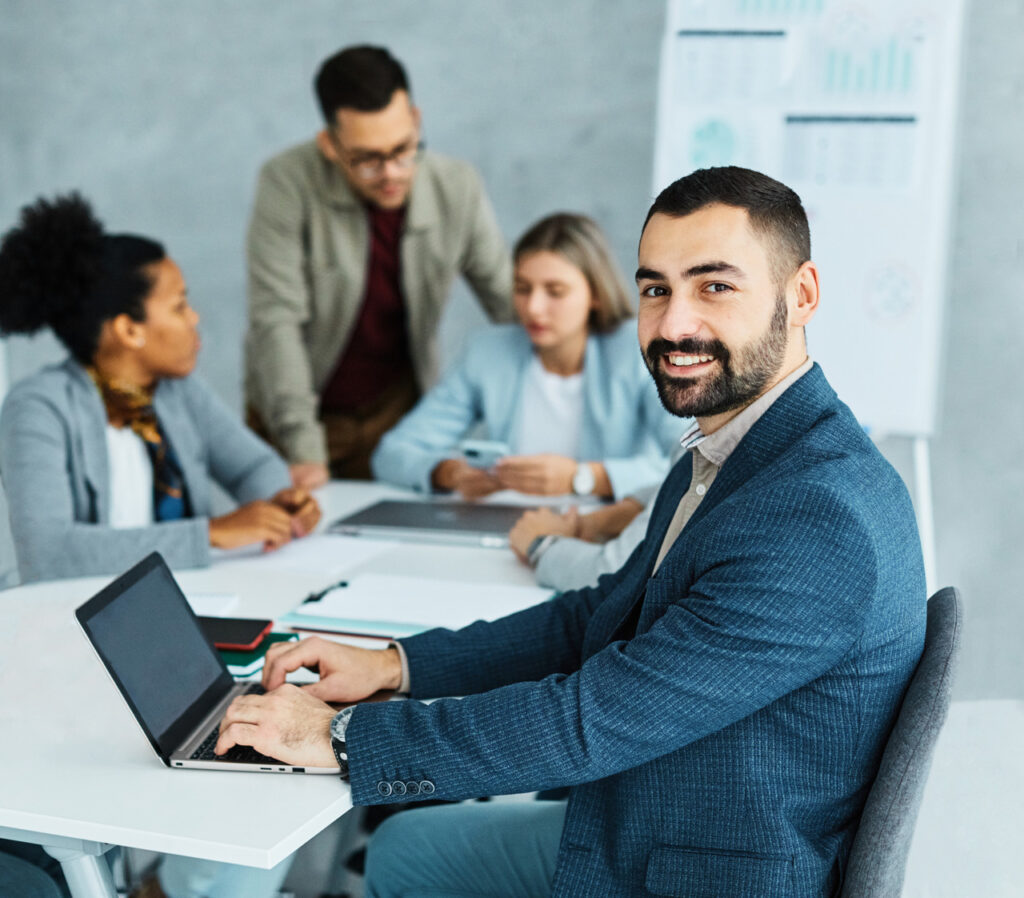 Young business people sit around a table with laptops